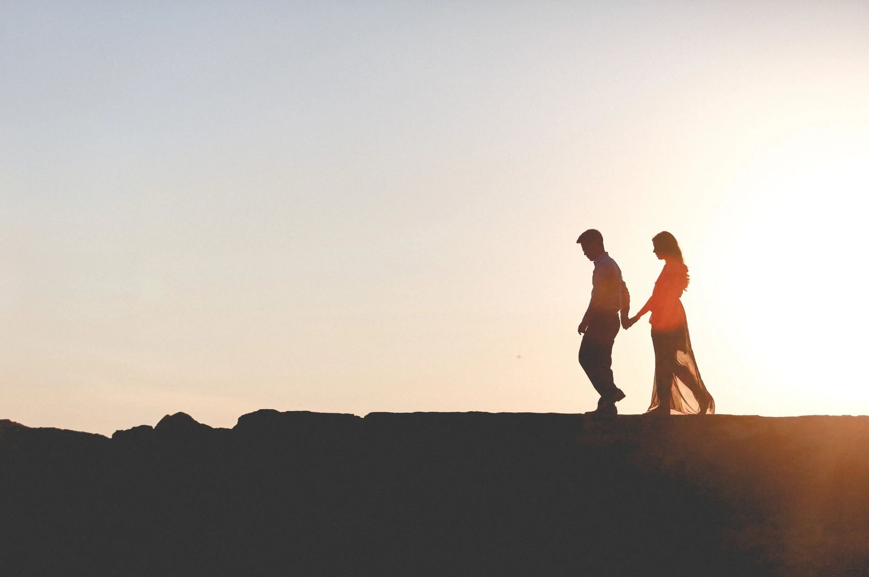 A couple walking hand in hand at dusk